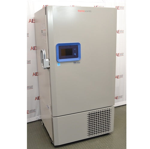 A left-side angled view of the grey Thermo Scientific RDE60086FA ultra-low temperature freezer, displaying the side-mounted handle, blue control panel, and front ventilation grille against an American Instrument Exchange backdrop.