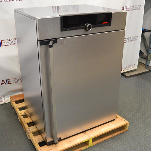 Angled front-left view of a Memmert HPP260 climate chamber resting on a wooden shipping pallet, highlighting the textured stainless steel exterior, vertical door handle, and top digital control panel.