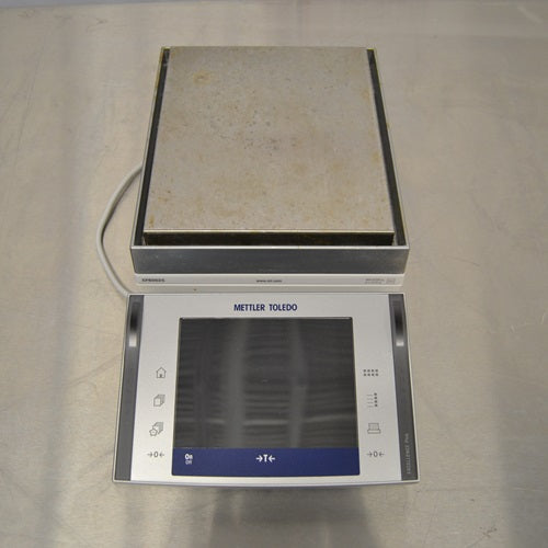 Top view of a Mettler Toledo XPE6002S precision balance with a large rectangular weighing pan and digital touchscreen control terminal.
