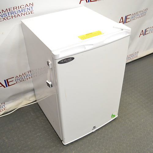 Compact white Norlake undercounter laboratory freezer with a solid front door and key lock.