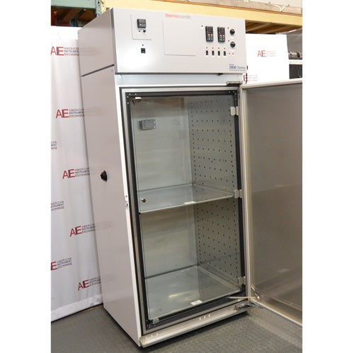 An angled open-door view of a Thermo Forma 3940 refrigerated environmental chamber in front of an American Instrument Exchange backdrop, highlighting the open outer door, internal glass door, shelf interior, and top grey control console.