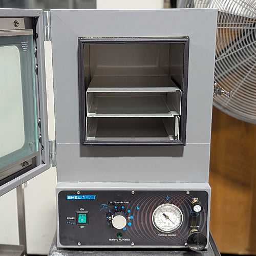 Open chamber view of Shel-Lab SVAC1E vacuum oven showing internal metal shelves and lower control panel