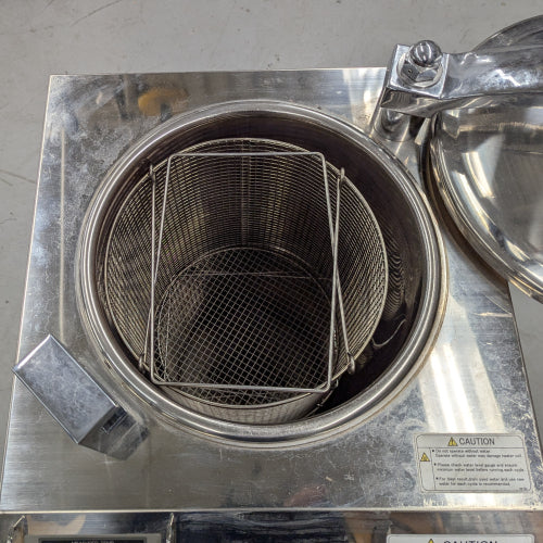 Open stainless steel chamber of Yamato Scientific SM511 vertical steam sterilizer autoclave showing internal wire basket