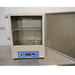 An open front view of a Thermo Scientific PR305225M Precision mechanical convection oven resting on a stainless steel surface in front of an American Instrument Exchange backdrop, with its front door swung open to reveal the interior chamber housing two wire rack shelves and the bottom blue control panel.