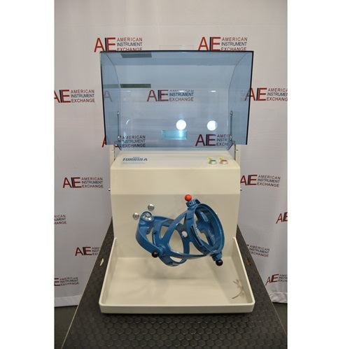 A front-facing view of the Willy A. Bachofen TURBULA T2 three-dimensional shaker mixer with its blue transparent safety shield lifted open, standing in front of an American Instrument Exchange backdrop.