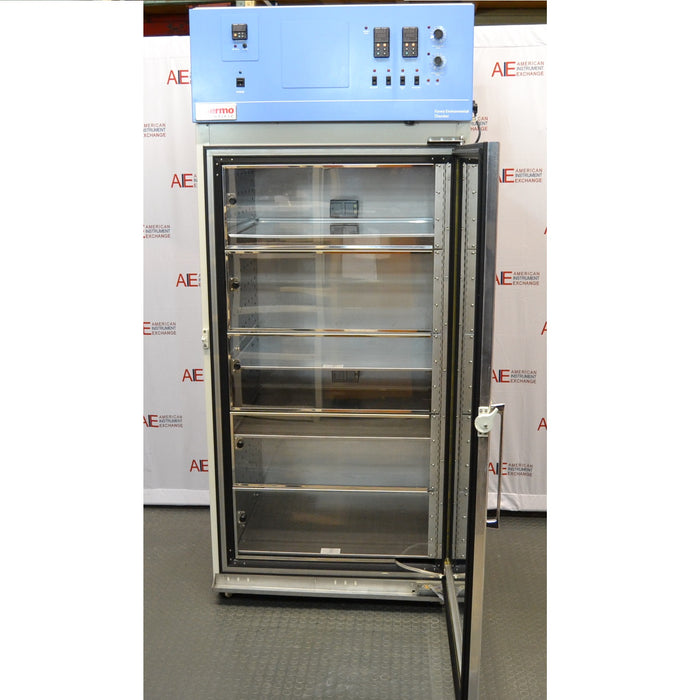 An open front-facing view of a Thermo Forma 3920 environmental chamber in front of an American Instrument Exchange backdrop, displaying its interior shelving and top control console.
