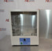 An open-door view of a Thermo Scientific PR305225G Precision laboratory oven sitting on a stainless steel surface, showing its interior stainless steel chamber, two wire racks, open front door, and blue control panel.