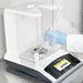 A gloved laboratory technician using a micro-spatula to dispense a sample onto the weighing pan inside the glass draft shield chamber of a Sartorius Secura 120 analytical balance showing an active digital touchscreen display.