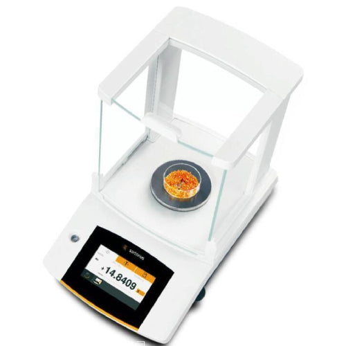 High-angle view of a Sartorius Secura 120 g semi-micro balance showing an orange granular sample in a clear dish on the weighing pan inside the glass draft shield chamber and an active color touchscreen display.