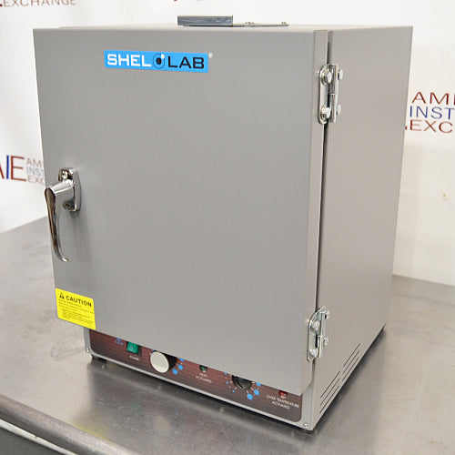 A gray Shel Lab SGO1E Economy Gravity Oven with a front door, control panel, and a caution sticker.