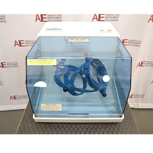 A Willy A. Bachofen TURBULA T2 three-dimensional shaker mixer enclosed in a blue transparent safety housing, positioned in front of an American Instrument Exchange backdrop.