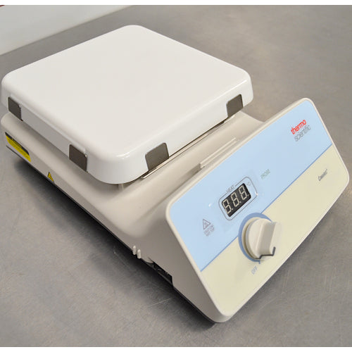 Three-quarter side-angled studio view of a Thermo Scientific Cimarec+ hot plate resting on a metallic work surface, showing the white ceramic top plate, sloping control panel with digital LED display, and rotary knob
