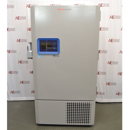 A full-length view of a grey Thermo Scientific RDE60086FA ultra-low temperature freezer, featuring a blue digital control panel and front grille, standing in front of an American Instrument Exchange backdrop.