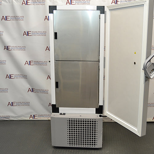  Straight-on studio view of a Thermo Scientific TSX40086 upright ultralow temperature freezer standing on a grey floor against a branded backdrop, featuring a solid grey outer door, ergonomic handle, integrated blue digital touchscreen interface, TSX Series branding, and a lower perforated ventilation panel