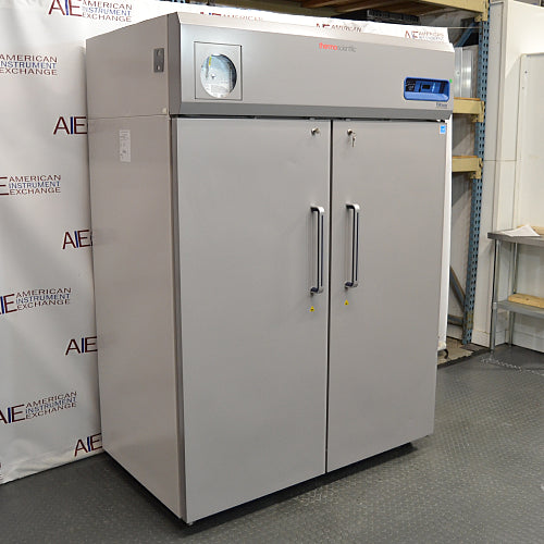 Angled view of a closed Thermo Scientific TSX5005SA double solid-door laboratory refrigerator showing the front handles, left side panel, and top control interface.