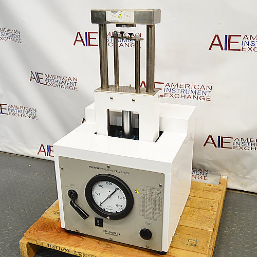An SLM Aminco French press, primarily white and silver in color, with pressure adjustment dials and a logo on the side, placed against a white background with 'American Instruments' logo in the top corner.