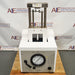 An SLM Aminco French press, primarily white and silver in color, with pressure adjustment dials and a logo on the side, placed against a white background with 'American Instruments' logo in the top corner.