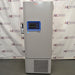 Straight-on studio view of a Thermo Scientific TSX40086 upright ultralow temperature freezer standing on a grey floor against a branded backdrop, featuring a solid grey outer door, ergonomic handle, integrated blue digital touchscreen interface, TSX Series branding, and a lower perforated ventilation panel