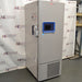 Straight-on studio view of a Thermo Scientific TSX40086 upright ultralow temperature freezer standing on a grey floor against a branded backdrop, featuring a solid grey outer door, ergonomic handle, integrated blue digital touchscreen interface, TSX Series branding, and a lower perforated ventilation panel