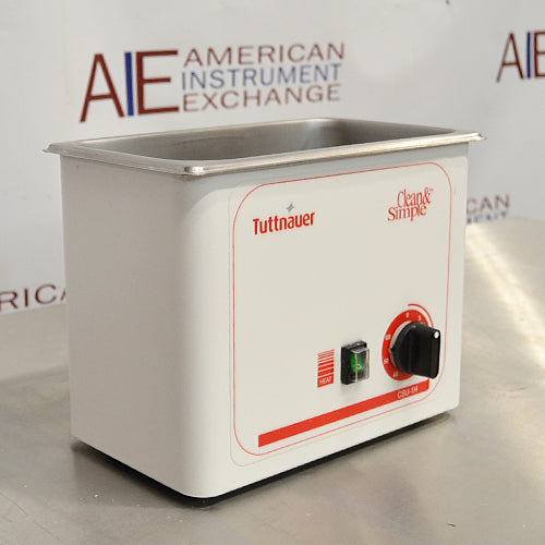 Angled front view of a Tuttnauer Clean & Simple CSU1H ultrasonic cleaner showing the stainless steel tank basin, green heat power switch, and rotary timer knob.