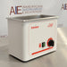 Angled front view of a Tuttnauer Clean & Simple CSU1H ultrasonic cleaner showing the stainless steel tank basin, green heat power switch, and rotary timer knob.