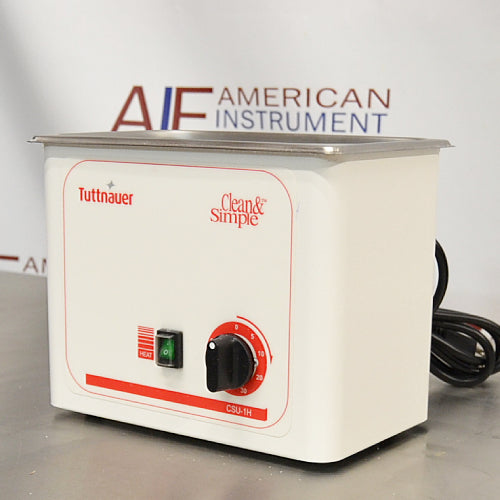 Angled view of a Tuttnauer Clean & Simple CSU1H ultrasonic cleaner showing the front panel with heat power switch, rotary timer knob, side casing, and attached power cord.