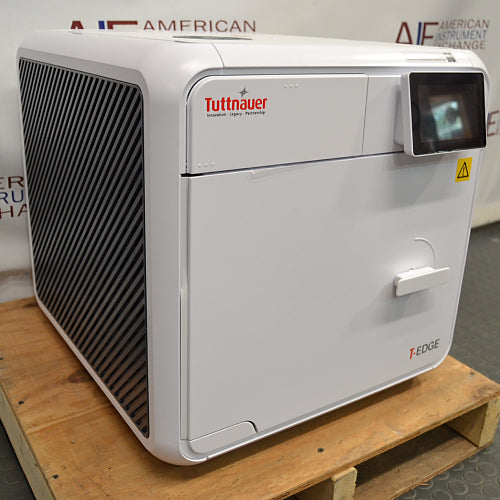 Angled view of a closed Tuttnauer T-Edge 11B tabletop autoclave showing the side ventilation grille, front door handle, and digital touchscreen.