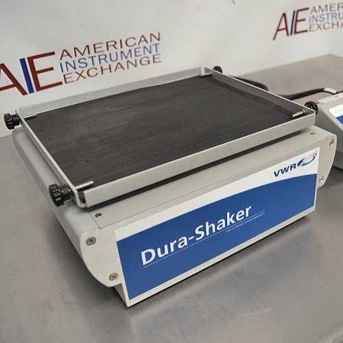 Three-quarter side-angled studio view of the VWR Advanced Dura-Shaker base unit resting on a stainless steel surface, featuring its front blue branding panel and top non-skid platform with securing clamps