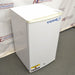 A white VWR undercounter laboratory refrigerator with a blue logo, standing on a floor with 'CAUTION' and 'SERVICE内部使用禁止' stickers on it.