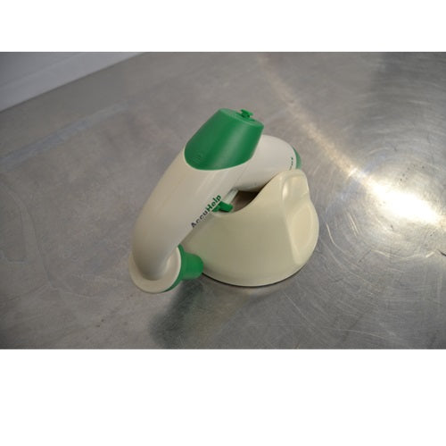 AccuPet AccuHelp motorized pipette controller, white with green accents, resting on a beige charging stand on a metal counter, seen in a side view