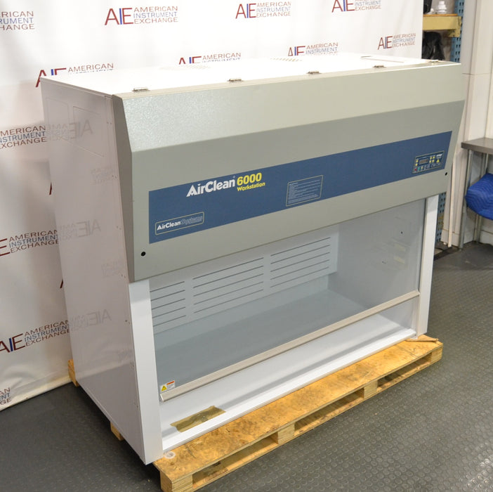 Right angled perspective view of an AirClean Systems AC6000S polypropylene ductless fume hood positioned on a wooden shipping pallet, showing its side panel, upper housing, and work chamber