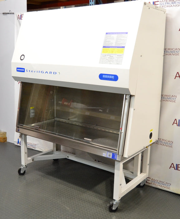 Right angled perspective view of a Baker SterilGARD e3 SG504 biosafety cabinet positioned on a mobile locking stand, showcasing its white exterior casing, stainless steel work zone, and upper brand decal