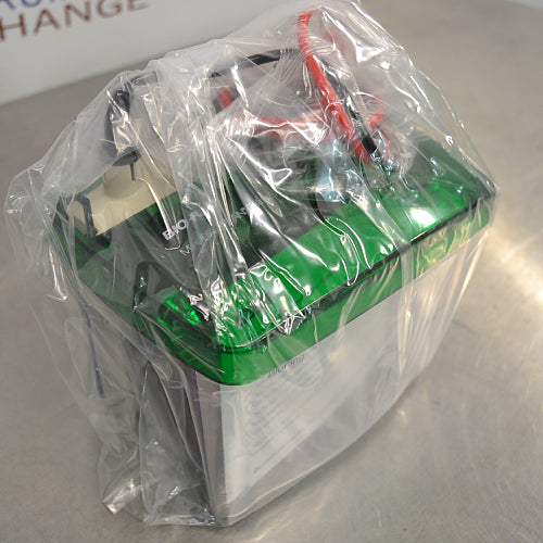 Left angle view of a Bio-Rad Mini Trans-Blot Cell module entirely enclosed in a clear plastic protective bag, showing the green safety lid and power cables underneath the packaging