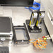 Close-up view of accessories for a BioTek Cytation 5 cell imaging multimode reader on a stainless steel surface, featuring dual CO2 and N2 gas flow meters on a stand, a specialized stage adapter insert, and a wired sensor harness