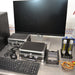 Front eye-level view of peripherals and accessories for a BioTek Cytation 5 cell imaging multimode reader, including a computer monitor, keyboard, mouse, dual aluminum storage cases, stage insert, and gas flow meters on a stainless steel counter