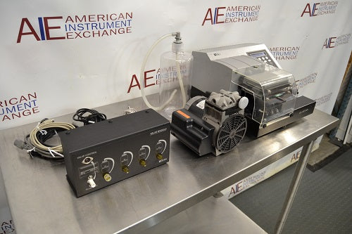 Right angled perspective view of a BioTek ELx405UV Select microplate washer system showcasing its valve module, cables, vacuum pump, and washer unit on a stainless steel tabletop