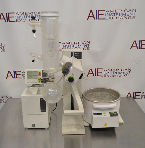Front eye-level view of Buchi R-100 rotary evaporator system showing vertical glass condenser, receiving flask, digital controller module, and heating bath