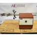 Front product view of a Burrell wrist action laboratory shaker, featuring its brown housing, front speed control dial, and horizontal shaker arm with multiple flask clamps resting on a wooden pallet base