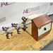 Left three-quarter angle product view of a Burrell wrist action laboratory shaker, featuring its brown and beige housing, speed control dial, and horizontal arm with multiple flask clamps on a wooden pallet