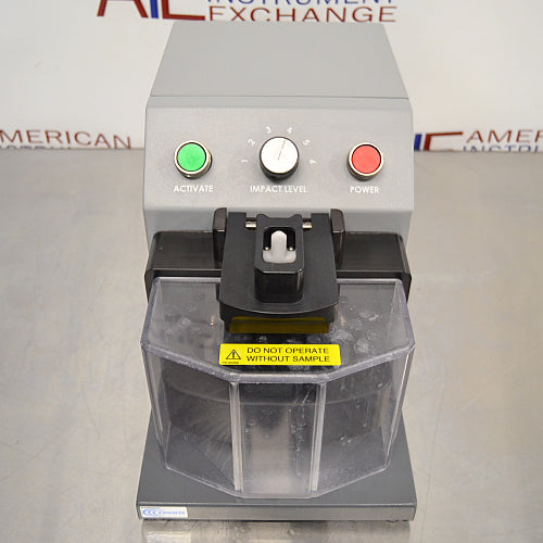 Elevated front product view of a Covaris cryoPREP CP02 dry pulverizer, showcasing its grey housing, clear protective front safety shield, central impact level dial, and control buttons