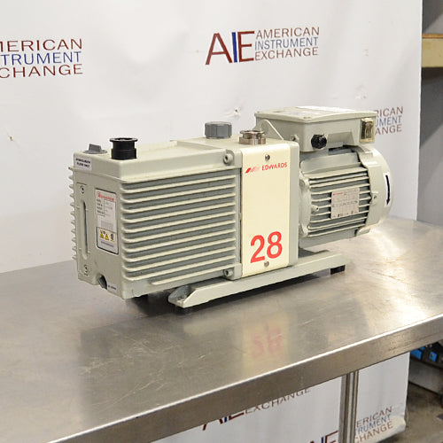 Left angle product view of an Edwards E2M28 rotary vane vacuum pump, featuring its gray finned housing, prominent red model number 28 label, and electric motor unit on a stainless steel surface