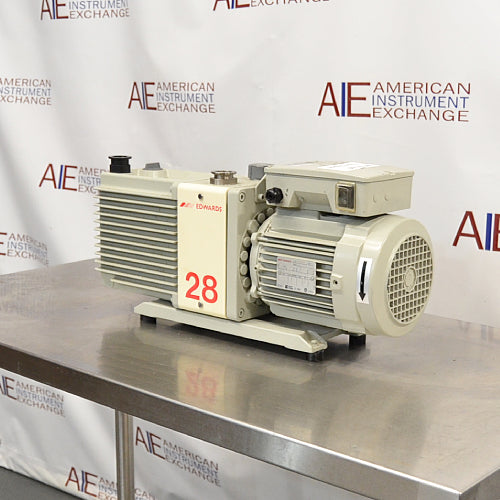 Right angle product view of an Edwards E2M28 rotary vane vacuum pump, featuring its gray finned housing, prominent red model number 28 label, and the rear electric motor fan housing on a stainless steel surface