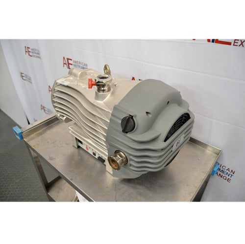 Three-quarter rear perspective view of an Edwards nXDS6i dry scroll vacuum pump resting on a stainless steel cart, showing its grey rear fan housing, exhaust fitting, and finned main body casing