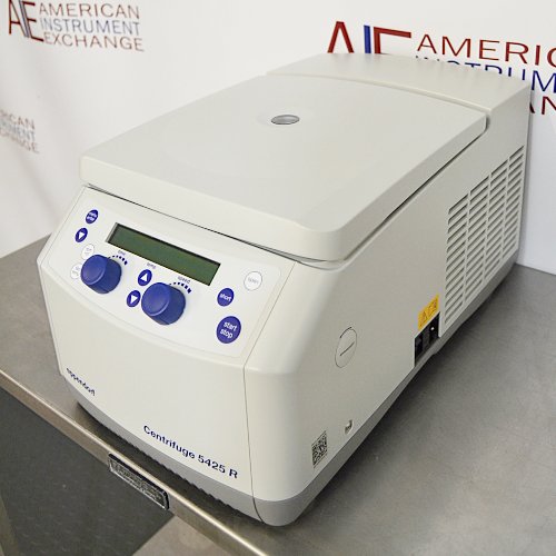 Right angled perspective view of an Eppendorf 5425R refrigerated microcentrifuge on a stainless steel surface, highlighting its light grey housing, closed lid, side ventilation vents, and front control panel with dual blue knobs