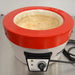 Front product view of a Fisatom laboratory heating mantle, highlighting its red and white cylindrical housing, internal heating well, front control panel with speed dial, indicator light, and power cord on a lab bench