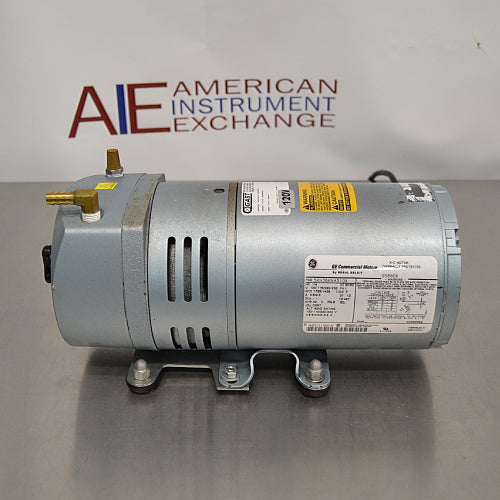 Gast diaphragm vacuum pump aur GE commercial motor ka side view, jisme electrical rating specifications label, mounting brackets, brass inlet/outlet fittings, aur cooling vents saaf dikhai de rahe hain.