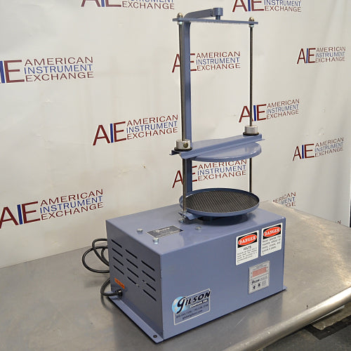 Left three-quarter angle product view of a Gilson 8-inch sieve shaker, highlighting its side ventilation louvers, vertical clamping rods, digital control panel, and power cord on a stainless steel lab bench