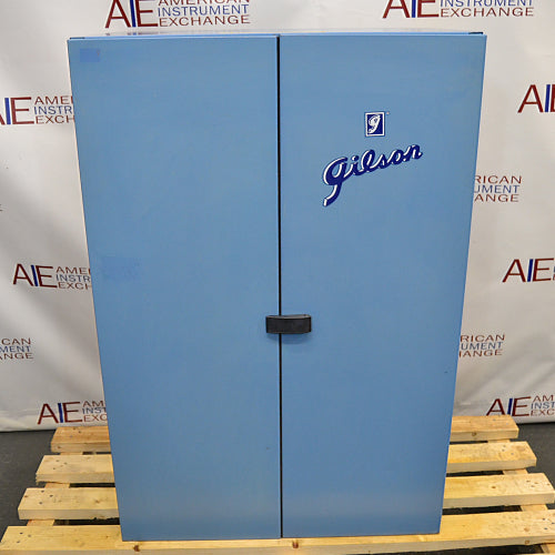 Straight-on front view of a closed blue Gilson sound enclosure cabinet for a sieve shaker, featuring double doors, the Gilson brand logo, and a center latch handle resting on a wooden pallet base