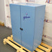 Left three-quarter angle product view of a closed blue Gilson sound enclosure cabinet for a sieve shaker, featuring double doors, the Gilson brand logo, and a center latch resting on a wooden pallet base