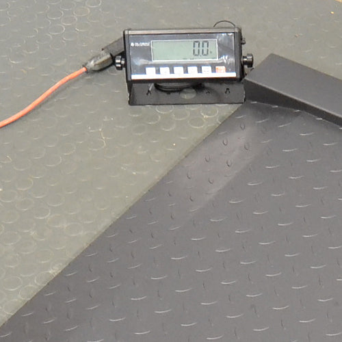 Close-up product view of a Global Industrial 318506 drum scale showing the digital LCD indicator console displaying zero weight, connected power cable, and textured diamond plate steel platform
